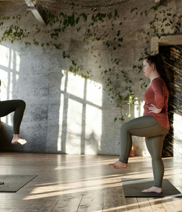 Smiling woman in sportswear stretching in a bright, sunlit room.